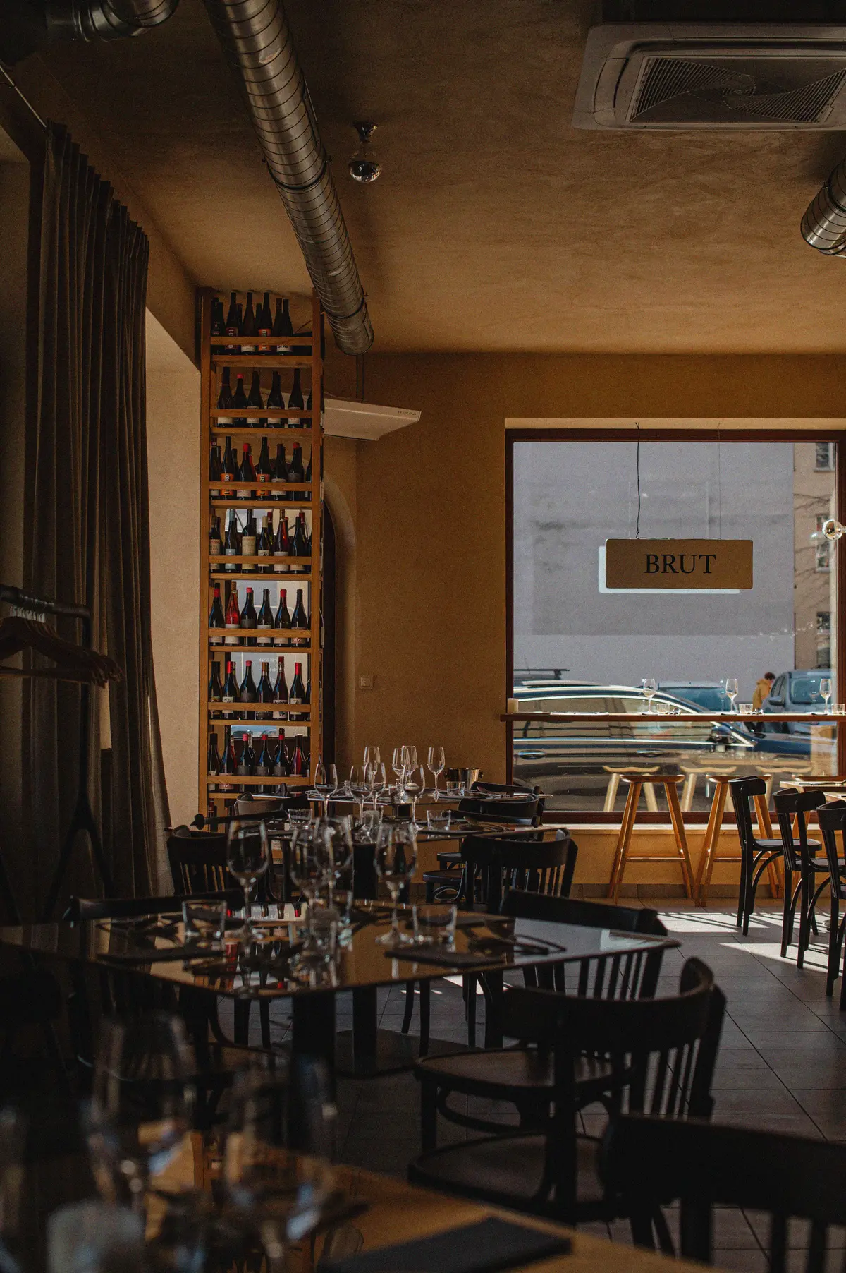 Der Gastraum des Brut Bistro — Weinregal an der Wand, gedeckte Tische, warmes Licht