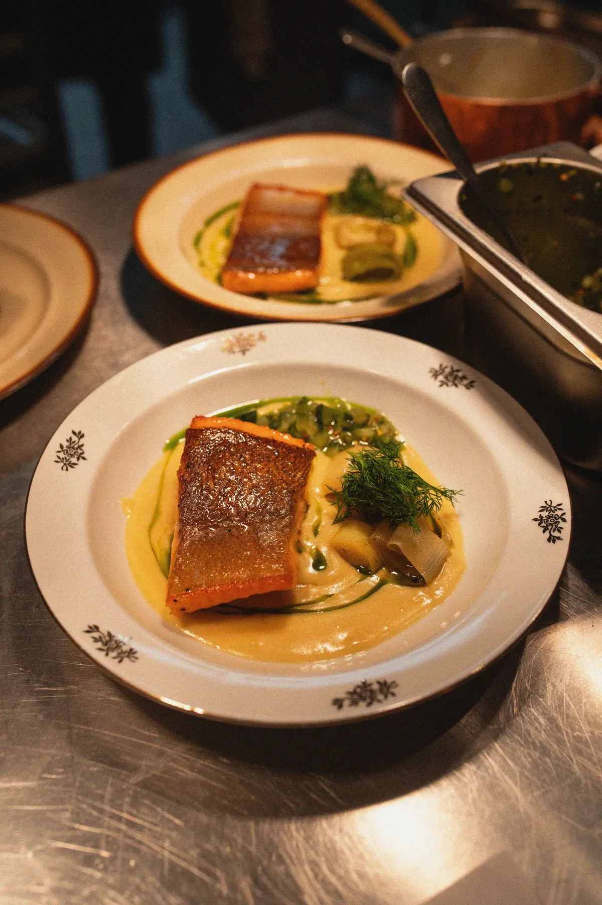 Fischgericht auf weißem Teller im Brut Bistro — zartes Filet mit Kräutern und Sauce auf Vintage-Porzellan