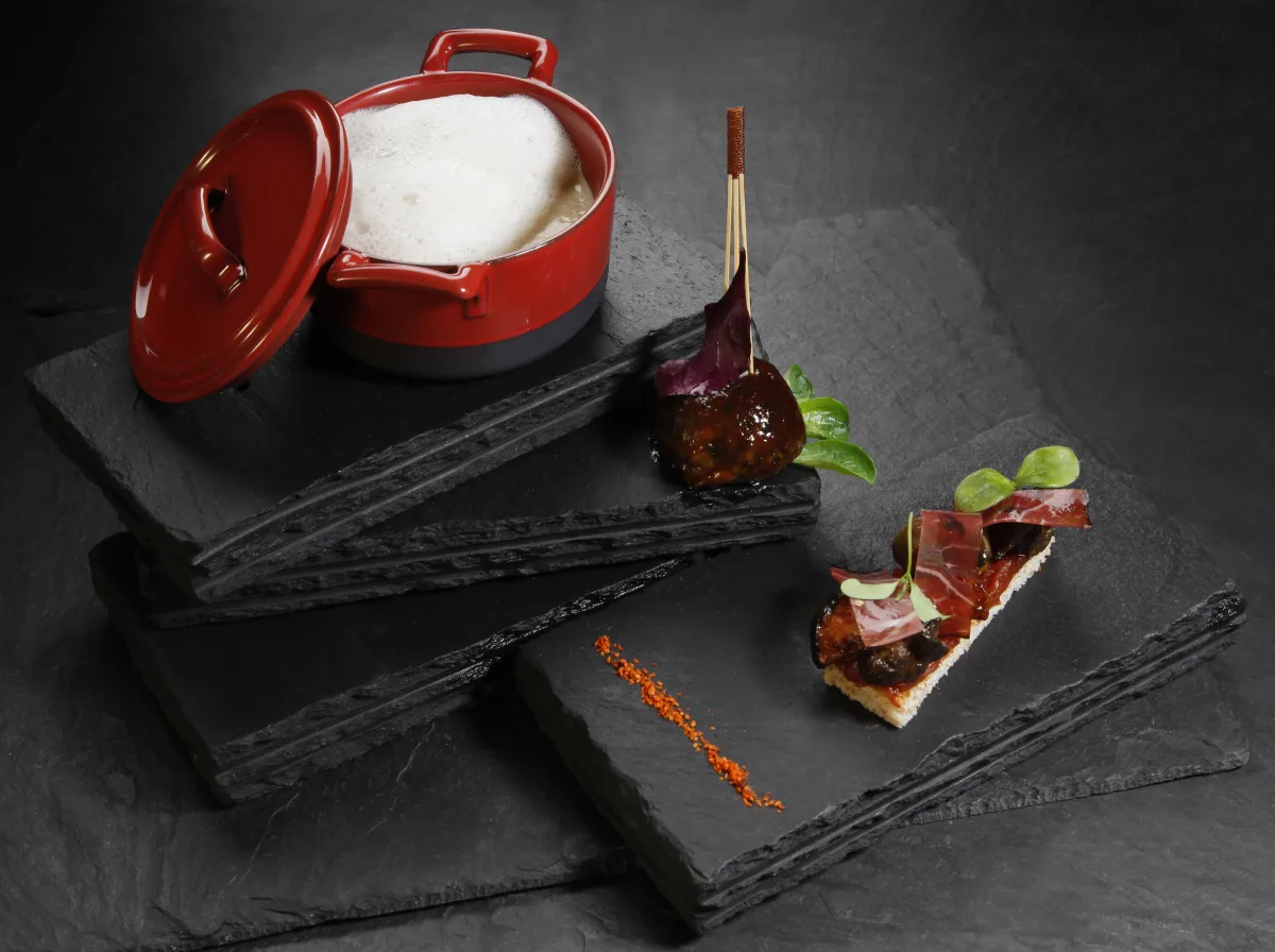 Minimalistisches Degustationsmenü-Gericht auf weißem Porzellan mit Kräuteröl und Mikroblüten