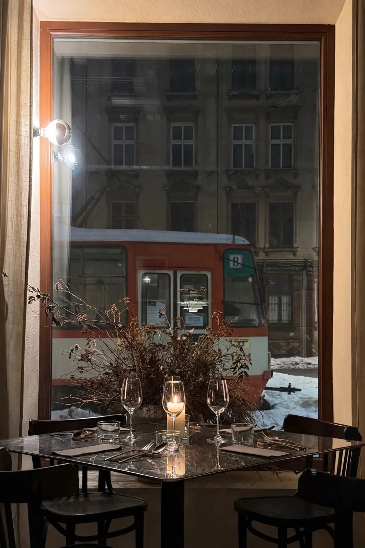 Fensterplatz im Brut Bistro bei Kerzenlicht — Weingläser auf dem Tisch, draußen die Niederstadt bei Nacht